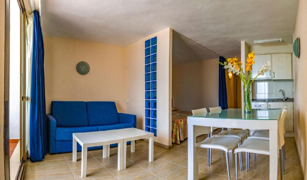 ein Wohnzimmer mit einem blauen Sofa und einem Tisch in der Unterkunft Apartamentos Complejo Eurhostal in Alcossebre