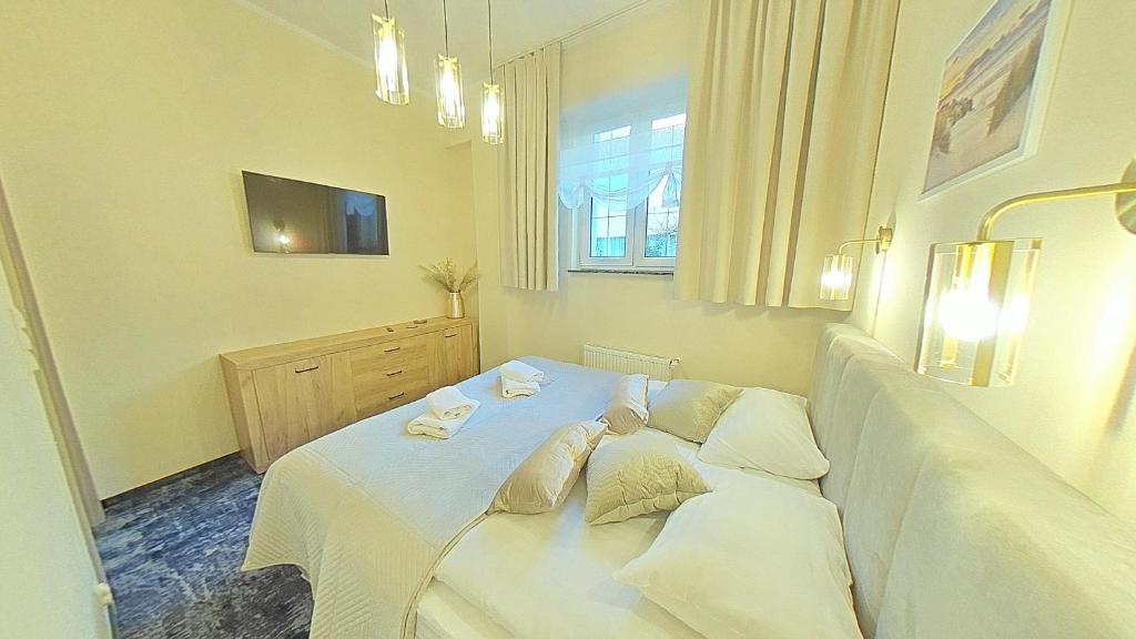 sypialnia z łóżkiem z białymi prześcieradłami i poduszkami w obiekcie Apartament ARKA w mieście Jarosławiec