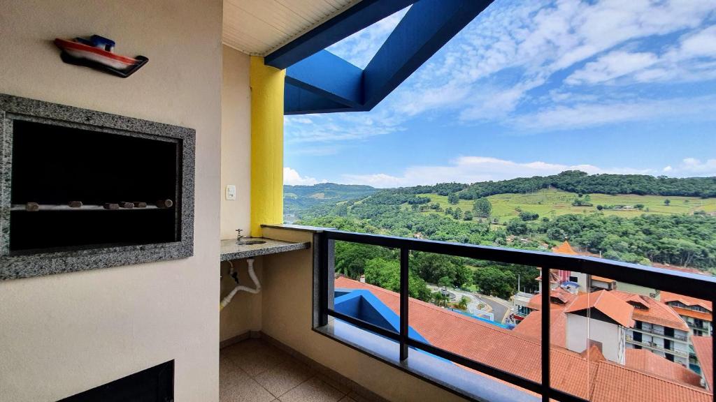 a room with a balcony with a large window with a view at Mirante das Aguas de Piratuba in Piratuba