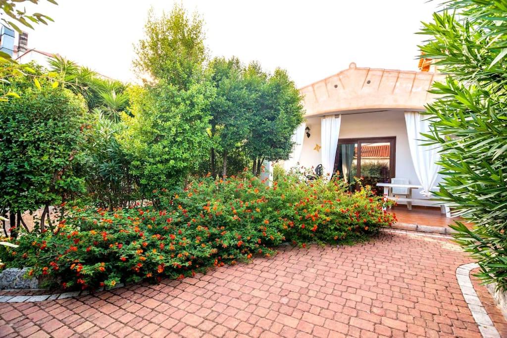 une passerelle en briques devant une maison fleurie dans l'établissement residence lu soli budoni affitti, à Budoni