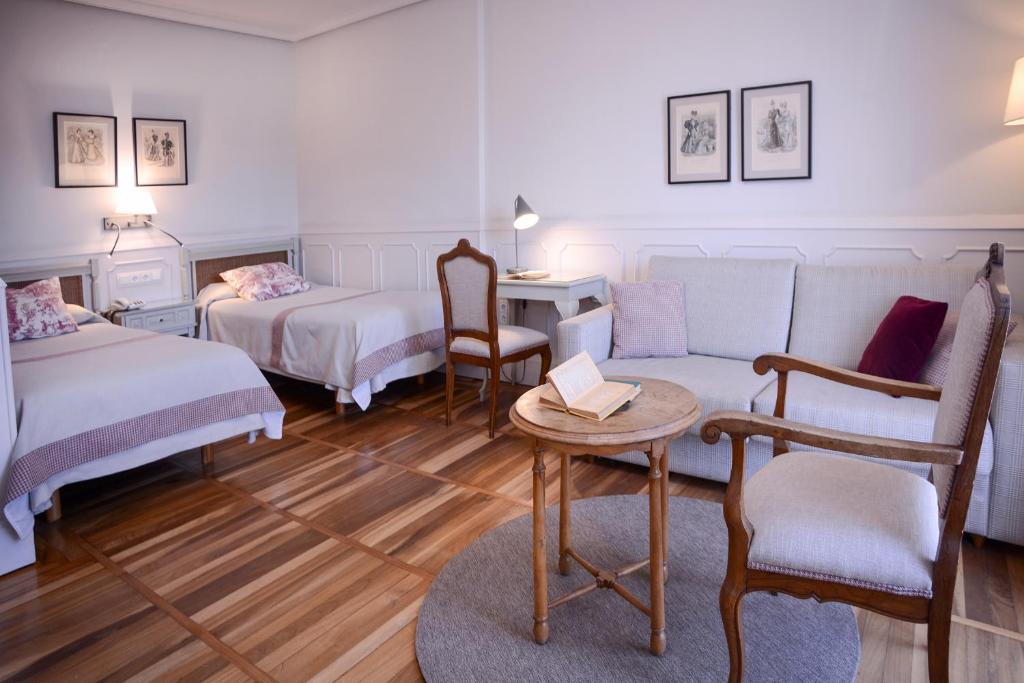 a room with two beds and a table and a couch at Hotel Alcazar Irun in Irún