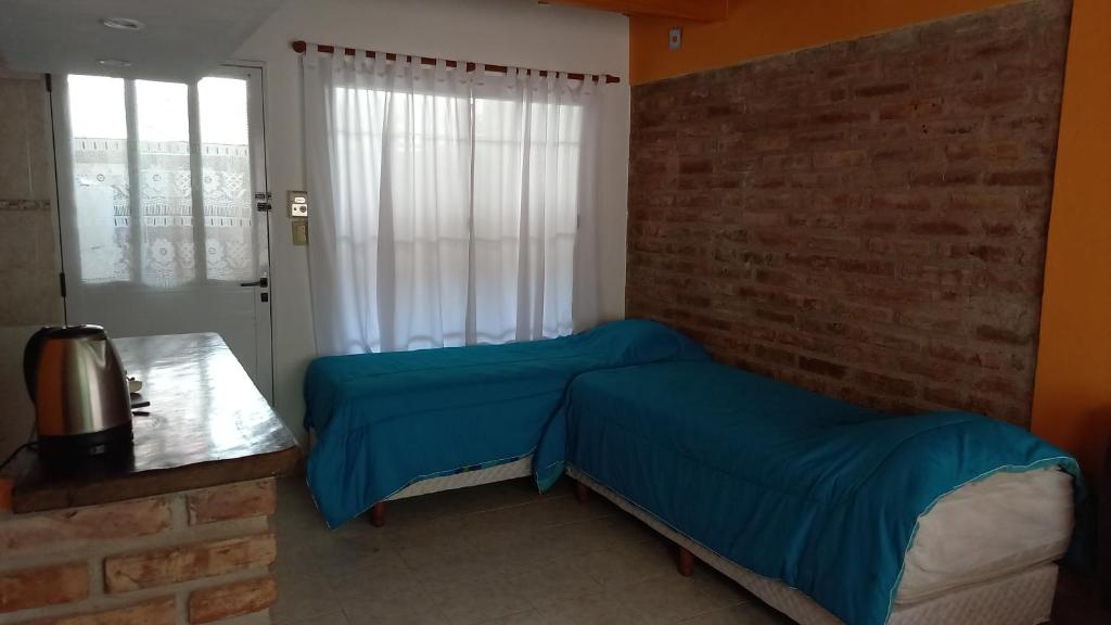 - une chambre avec 2 lits et un mur en briques dans l'établissement Rinconada 2, à Las Grutas