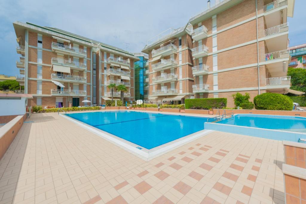 a swimming pool in front of two apartment buildings at Residence Puerto Del Sol Immobiliare Pacella in Lido di Jesolo