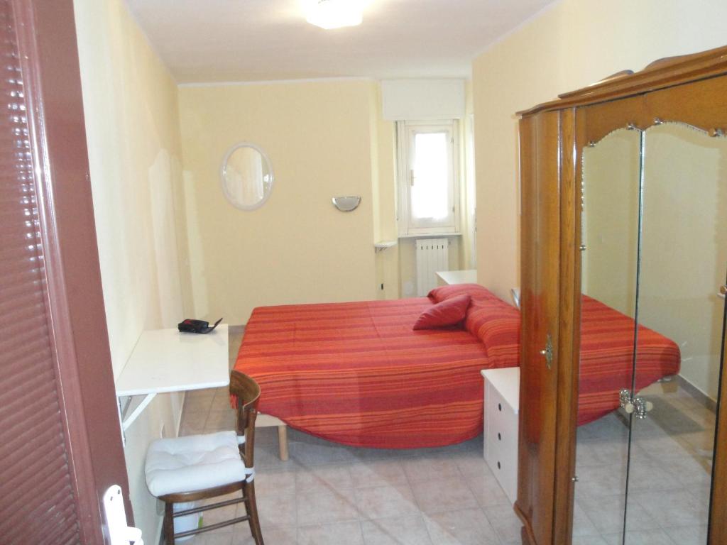 Monasterolo del CastelloにあるLa Piazza B&Bのベッドルーム1室(赤いシーツと椅子付きのベッド1台付)