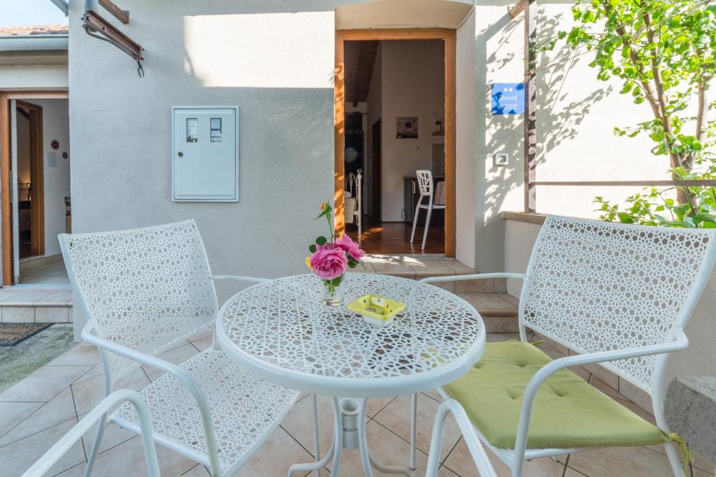 - une table et des chaises blanches sur la terrasse dans l'établissement Apartmani Bugenvilija, à Brbinj