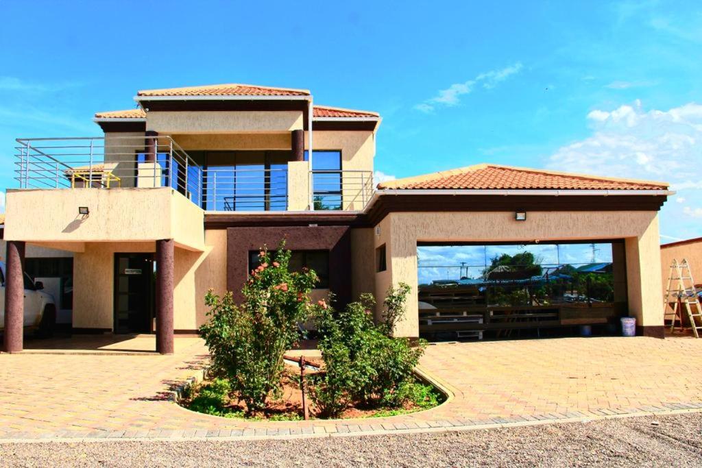 uma casa grande com uma varanda em cima em Rose Garden Guest House em Gaborone