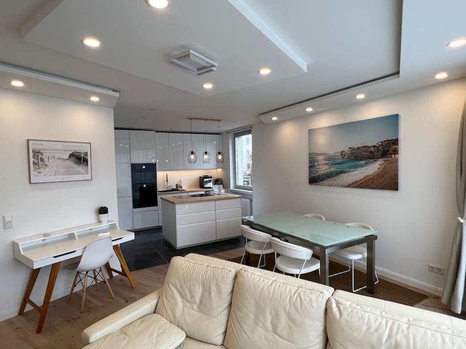 a living room with a white couch and a kitchen at Lovely HOME Suite in Nuremberg in Nürnberg