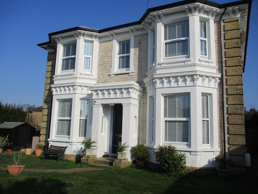 Una gran casa blanca con persianas blancas. en Lovely Spacious 3 Bedded First Floor Apartment, en Ryde