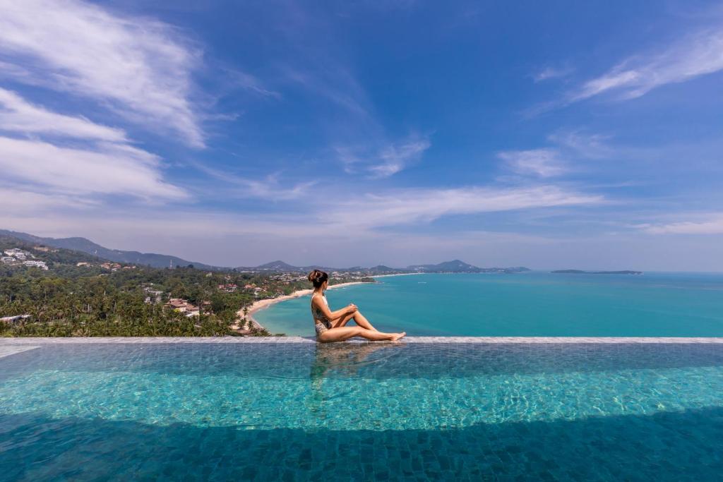 Una donna seduta sul bordo di una spiaggia di Villa Anushka - Modern luxury villa with picture-perfect sea views a Ko Samui