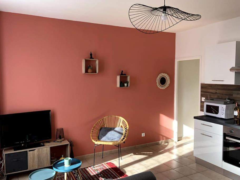 a living room with a red wall at Joli T2 en centre-ville de Rochefort in Rochefort