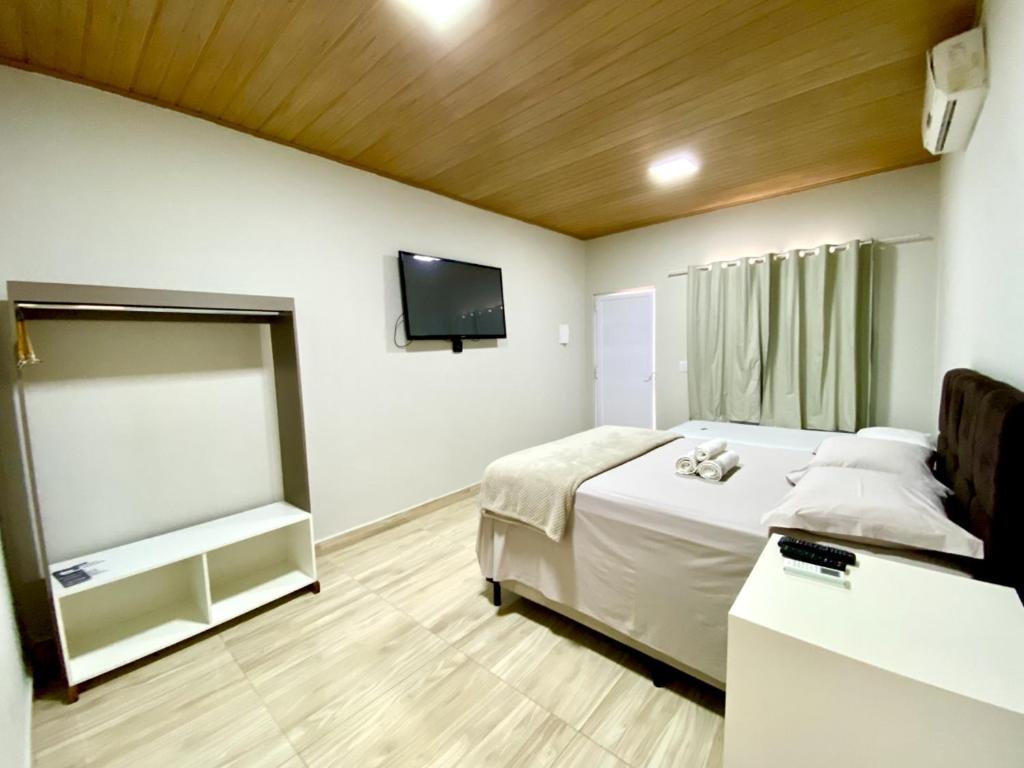 a bedroom with a bed and a flat screen tv at Pousada Lótus in Chapada dos Guimarães