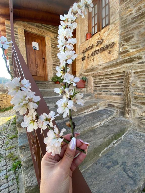 una persona sosteniendo un ramo de flores blancas delante de un edificio en Casa do Ti Latoeiro, en Torre de Moncorvo