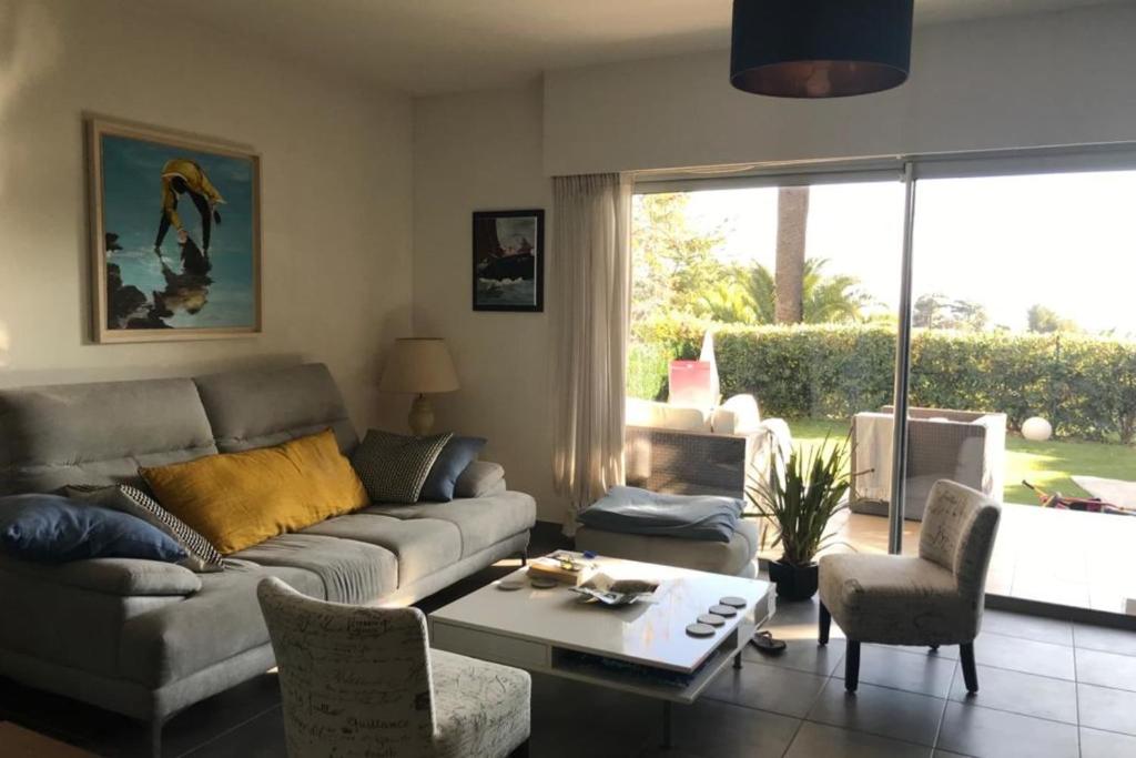 uma sala de estar com um sofá e uma mesa em Large Apartment with a large garden and a swimming pool in the residence em Antibes