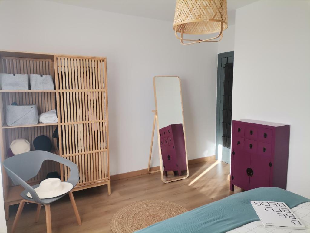 een slaapkamer met een bed, een stoel en een spiegel bij Villa Pepita in Almerimar