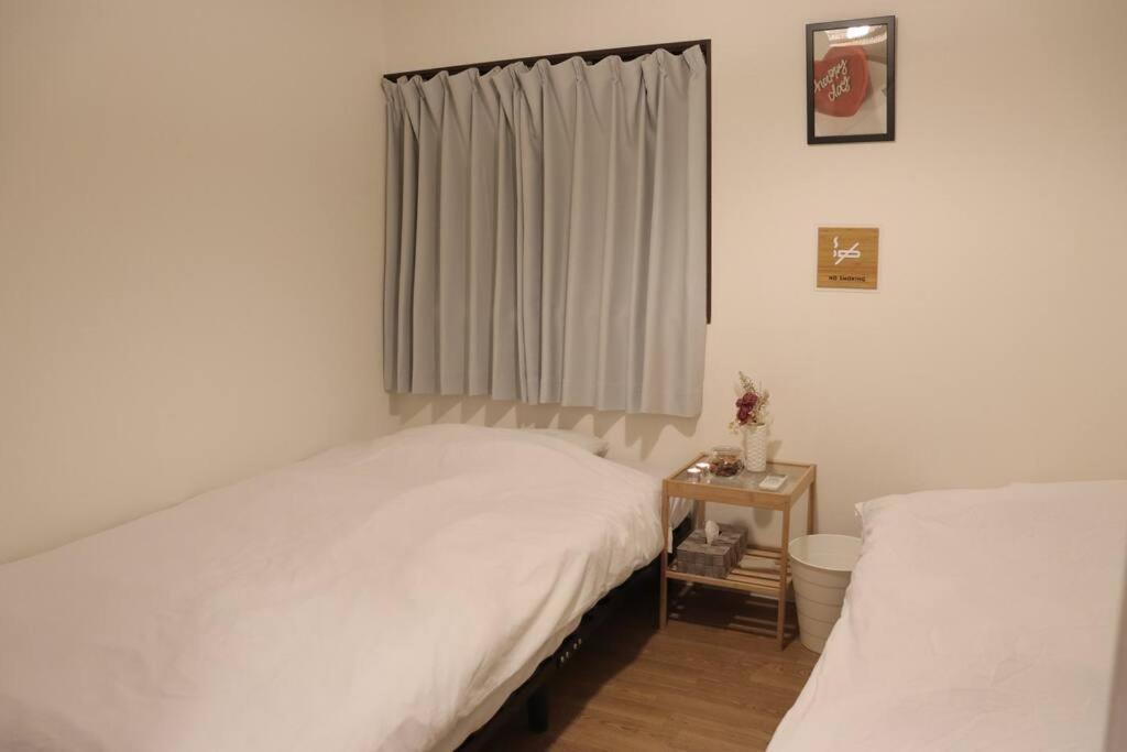 a bedroom with two white beds and a window at 天神橋筋六丁目駅徒歩2分！屋上テラス付き一軒家 天満居酒屋街2分 梅田10分 難波15分 最大13名 in Osaka
