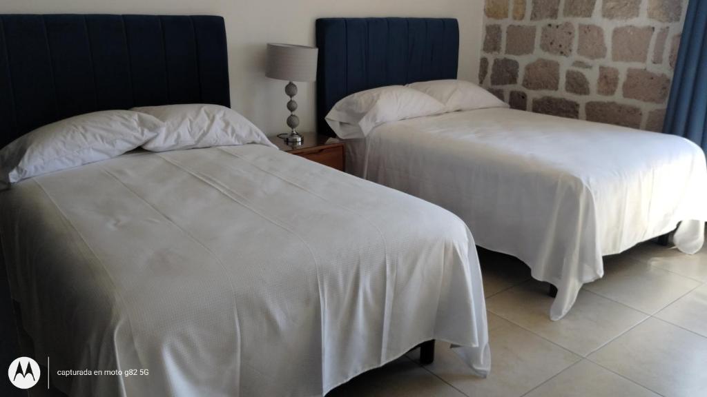 duas camas num quarto de hotel com lençóis brancos em Departamento Mamá Rosario em Morelia