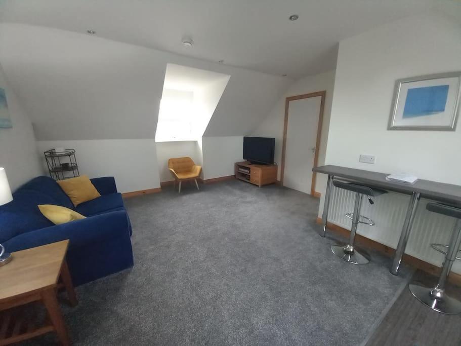The Apartment في Langley Park: غرفة معيشة مع أريكة زرقاء ومكتب