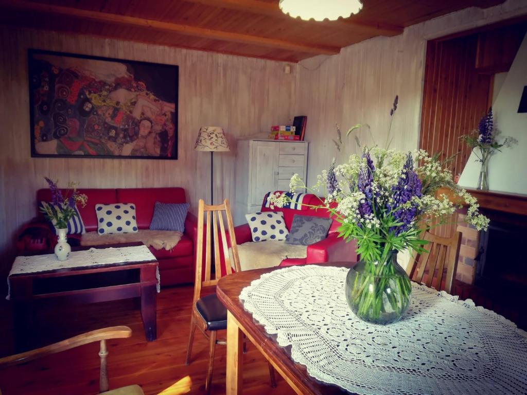 a living room with a table with a vase of flowers on it at Domek pod bukami in Szymbark