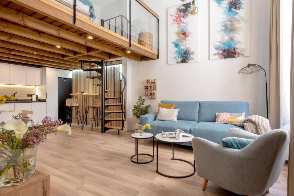 een woonkamer met een blauwe bank en een tafel bij Capricho de Quevedo in Sevilla