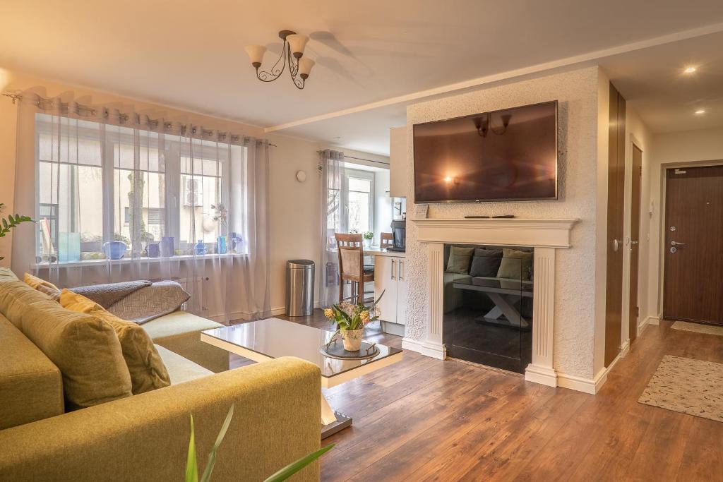 a living room with a couch and a television above a fireplace at Andrea Apartment in Liepāja