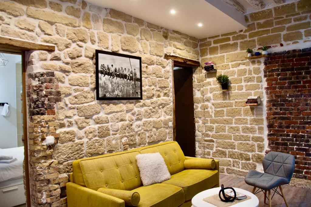 - un canapé jaune dans une pièce dotée d'un mur en briques dans l'établissement Sweet Virtue-Center of Paris, 2 Bedroom apartment, à Paris
