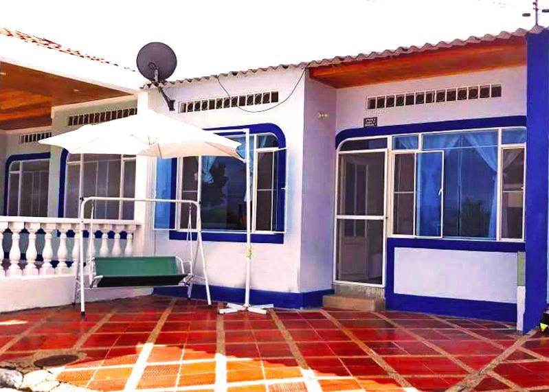 Casa azul y blanca con sombrilla en Acogedora casa condominio con piscina en Girardot, en Girardot