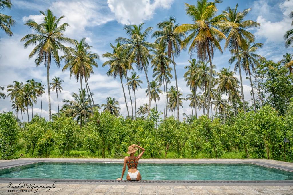 a woman standing in front of a swimming pool with palm trees at Tekkawatta in Colombo