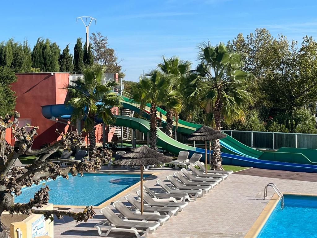 un complexe avec un toboggan, des chaises et une piscine dans l'établissement Camping L' Arlesienne, à Arles