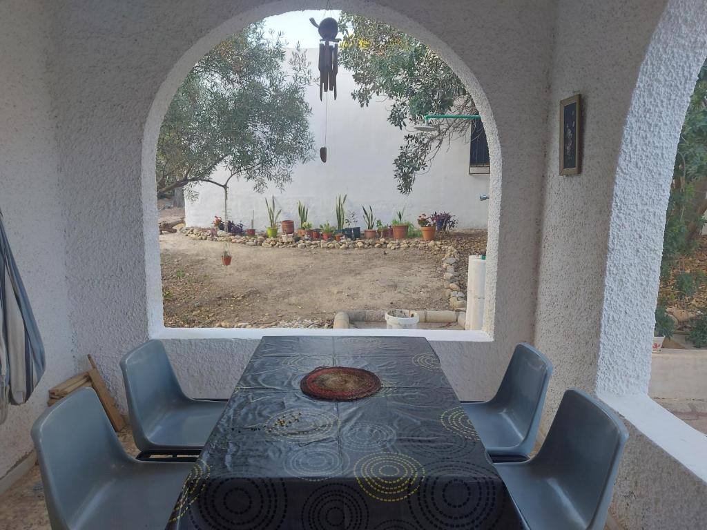 comedor con mesa, sillas y ventana en Cortijo tranquilo y espacioso entre el mar y desierto - Alborania, en Pechina