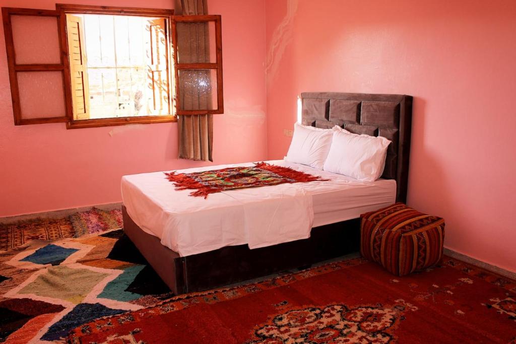 ein Schlafzimmer mit einem Bett in einem rosa Zimmer in der Unterkunft Pergolas Tamakouchte in Ouarzazate