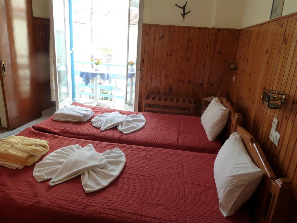 two beds in a room with red sheets and white towels at Hotel Dolphin in Pythagoreio