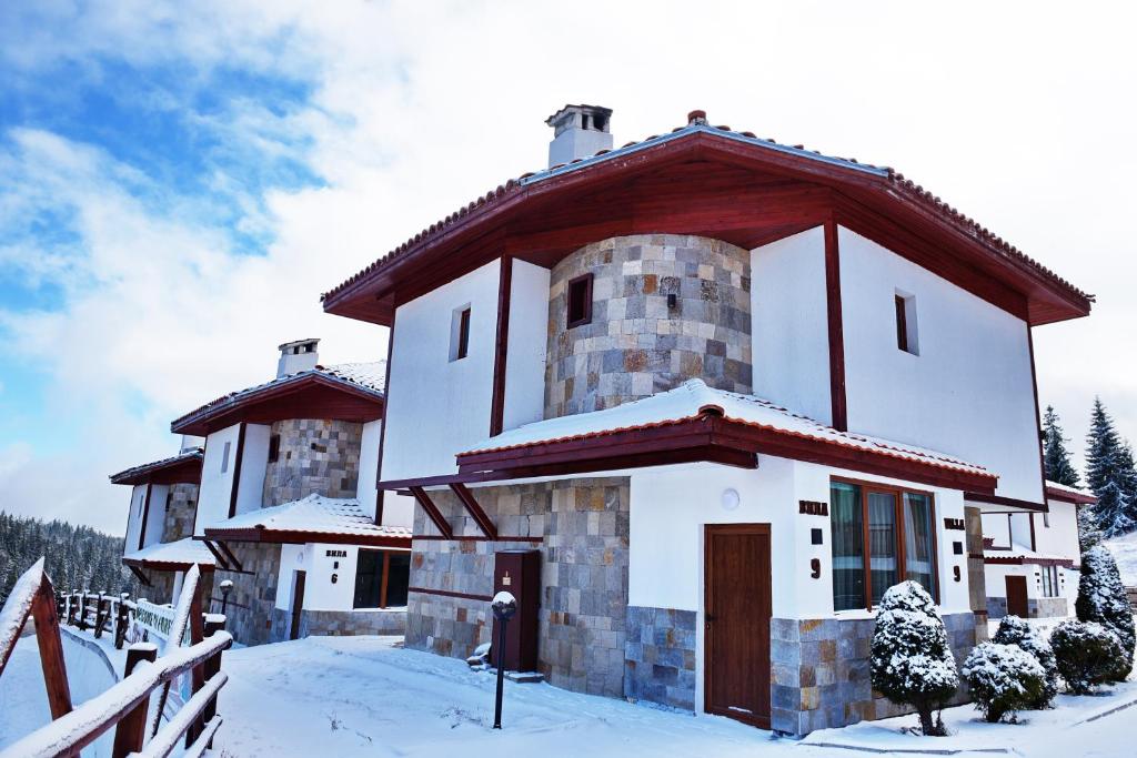 een groot gebouw met sneeuw op de grond bij Вили Forest Nook in Pamporovo