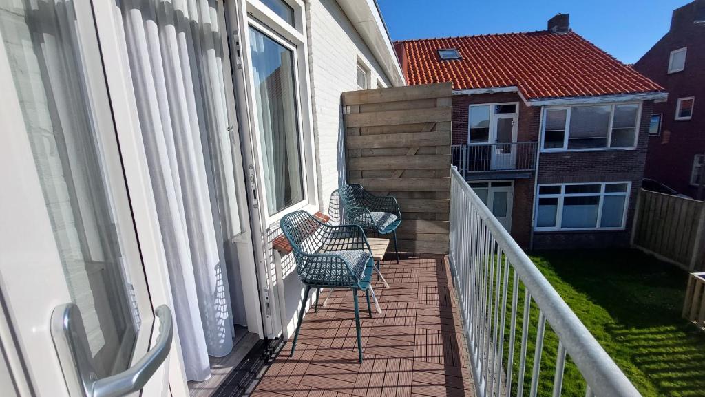 a balcony with two chairs on a house at Appartement vlakbij strand en centrum in Zoutelande