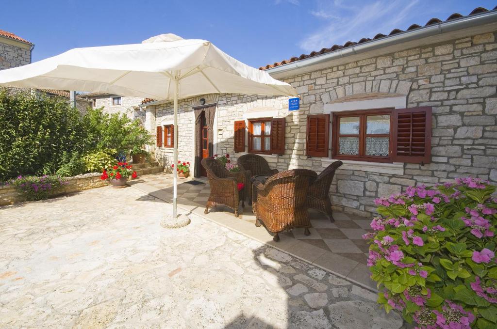 a patio with an umbrella and chairs and a house at Mon Perin Castrum - Apartment Ivan in Bale