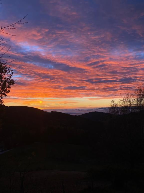 a sunset with the sun setting in the sky at Dein HimmelReich - Ruheoase im Almenland auf 1000m über'm Alltag 