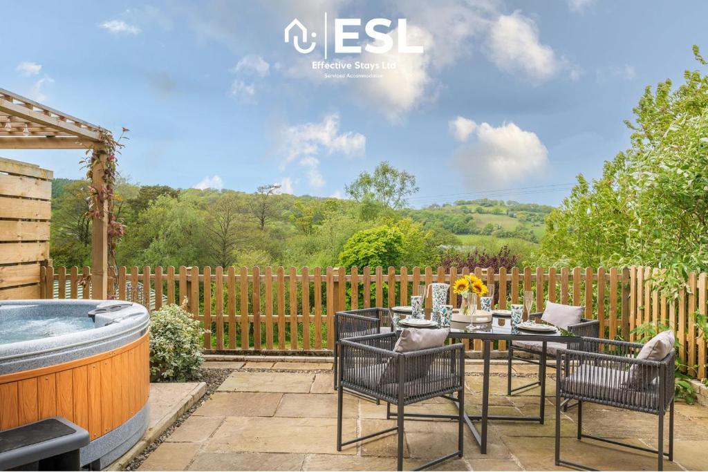eine Terrasse mit einem Tisch und Stühlen sowie einem Whirlpool in der Unterkunft Luxurious 2 Bedroom Countryside Hot Tub Retreat in Stiperstones in Shelve