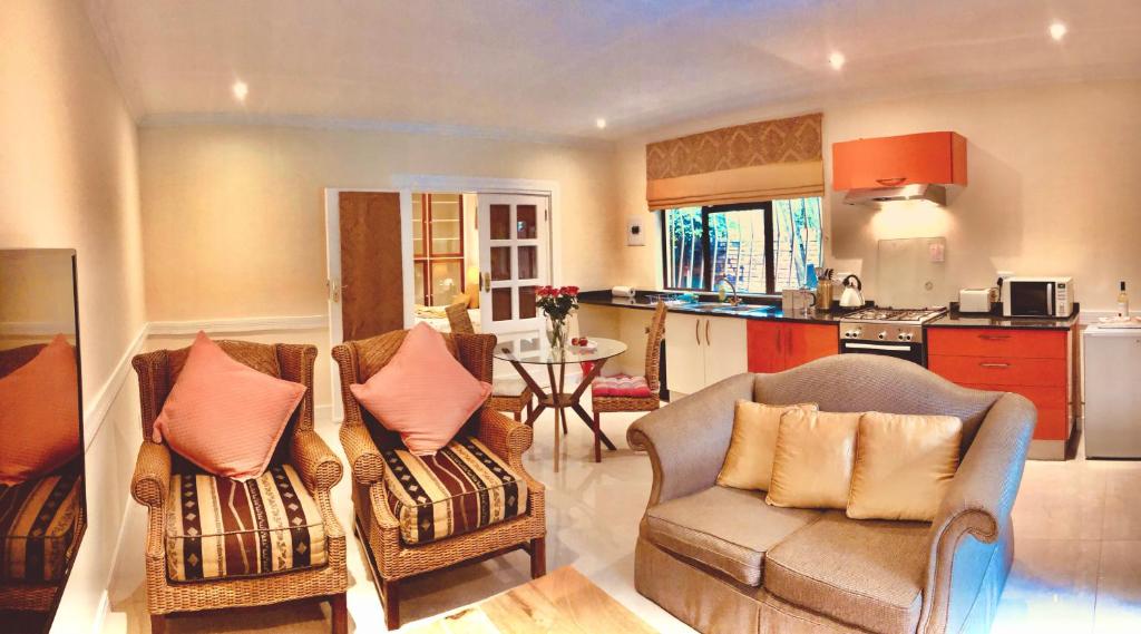 a living room with two chairs and a kitchen at 27A on Angus in Johannesburg
