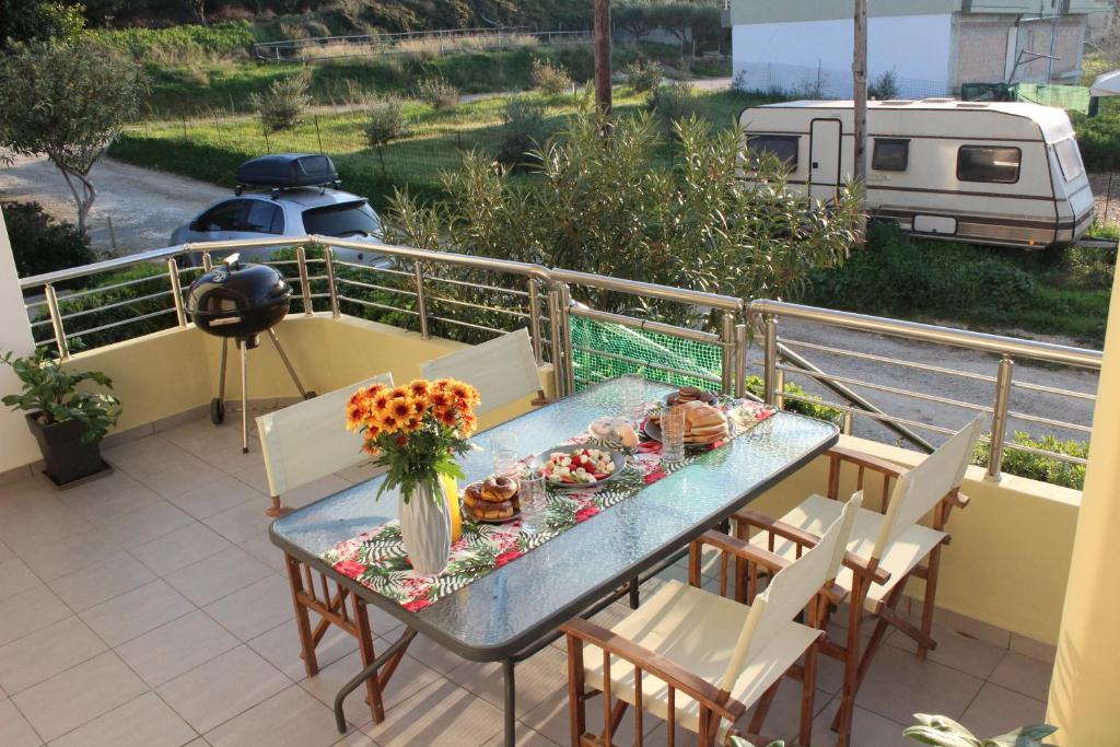 uma mesa e cadeiras numa varanda com comida e flores em Kallia's Modern Apartment em Kissamos