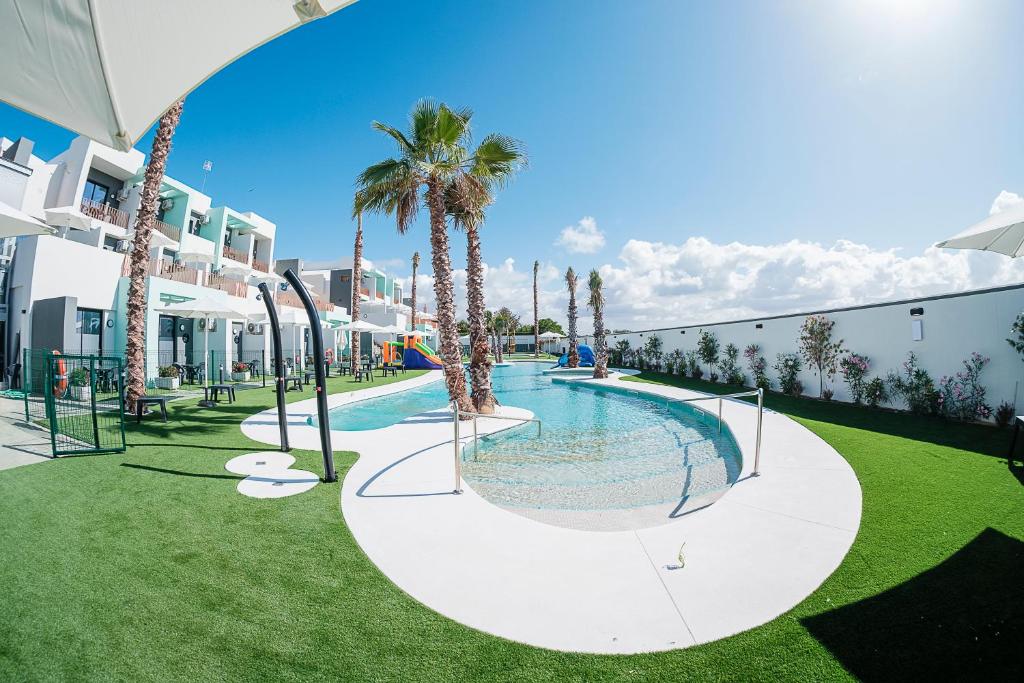 a swimming pool with palm trees in a resort at ON The Residence in Matalascañas