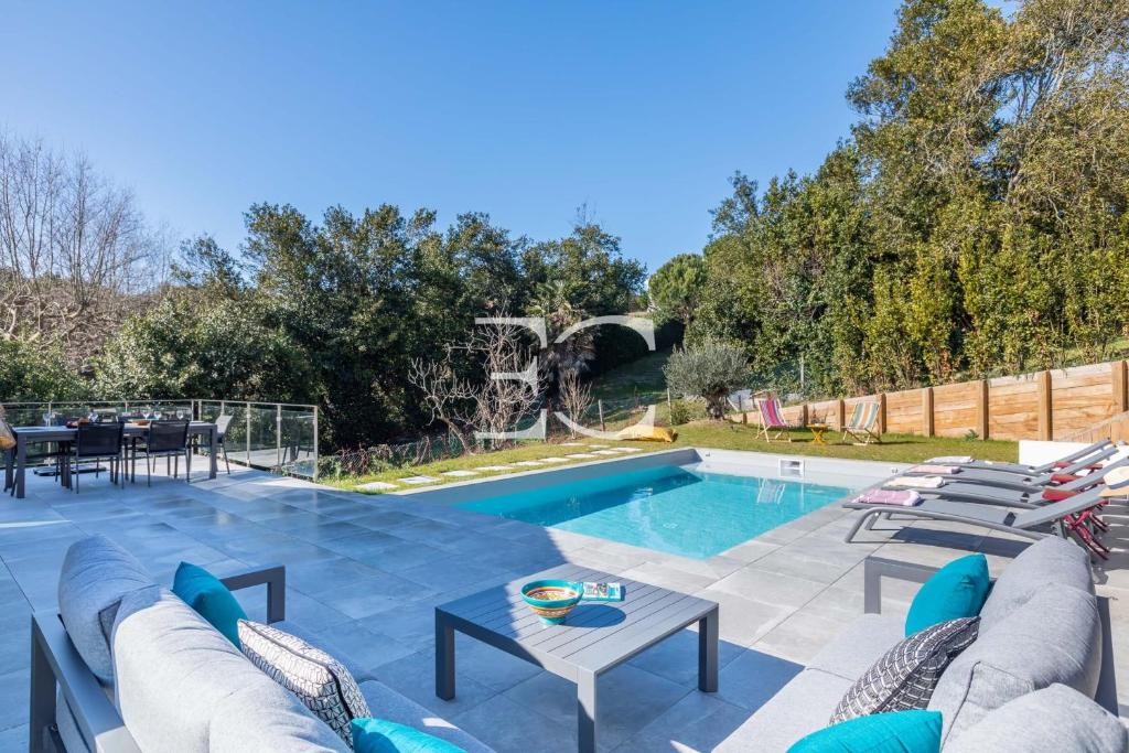 a pool with chairs and a table next to a pool at PROMO Easy Clés - 5 bedrooms villa heated pool AC in Saint-Jean-de-Luz