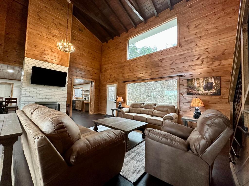 a living room with leather furniture and a large window at Creekfront Lodge: Brand new! in Pigeon Forge