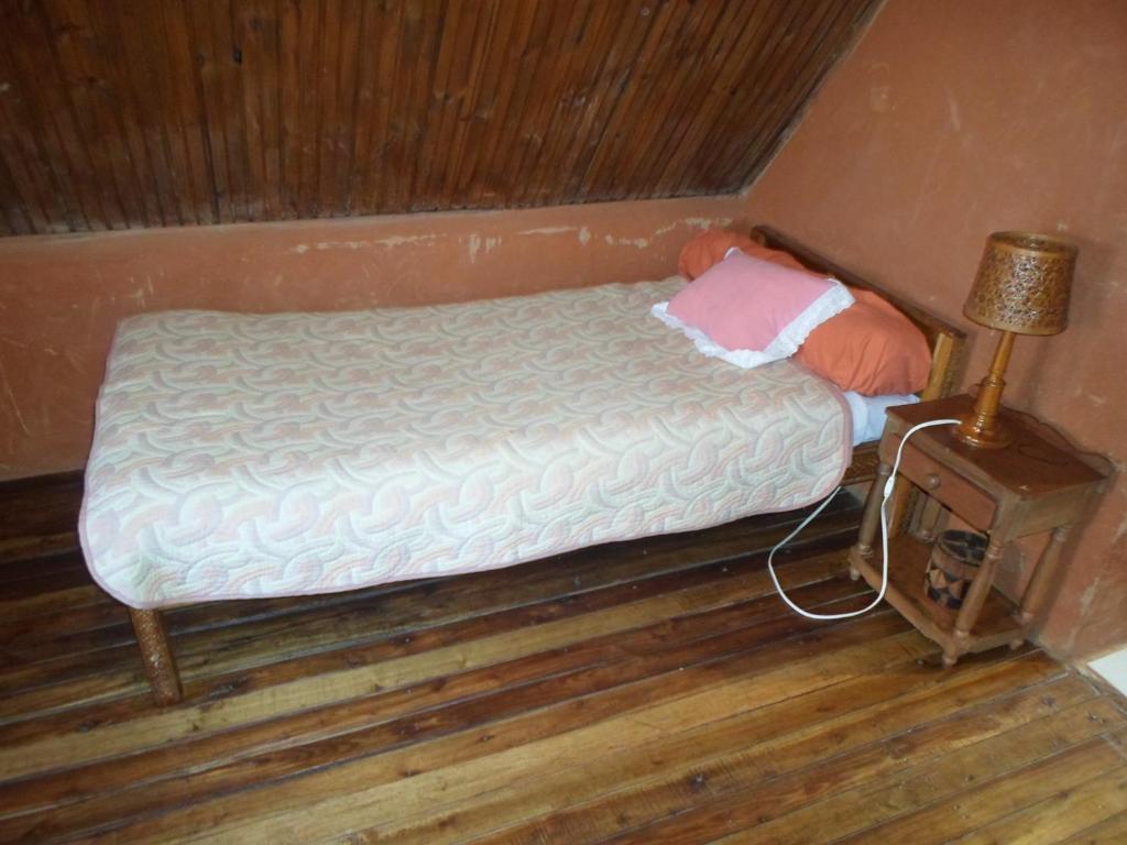 Cama pequeña en habitación con suelo de madera en Le Karthala Chambres D'Hotes, en Antananarivo
