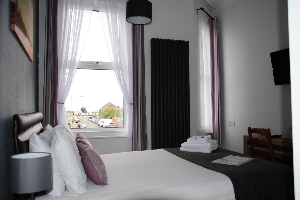 a hotel room with a bed and a window at Taunton House in Great Yarmouth