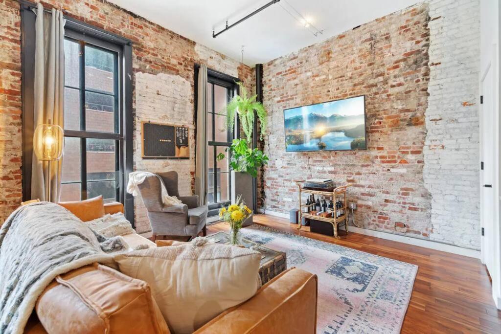 - un salon avec un mur en briques et un canapé dans l'établissement Luxurious Condo, Amazing Location, à Philadelphie