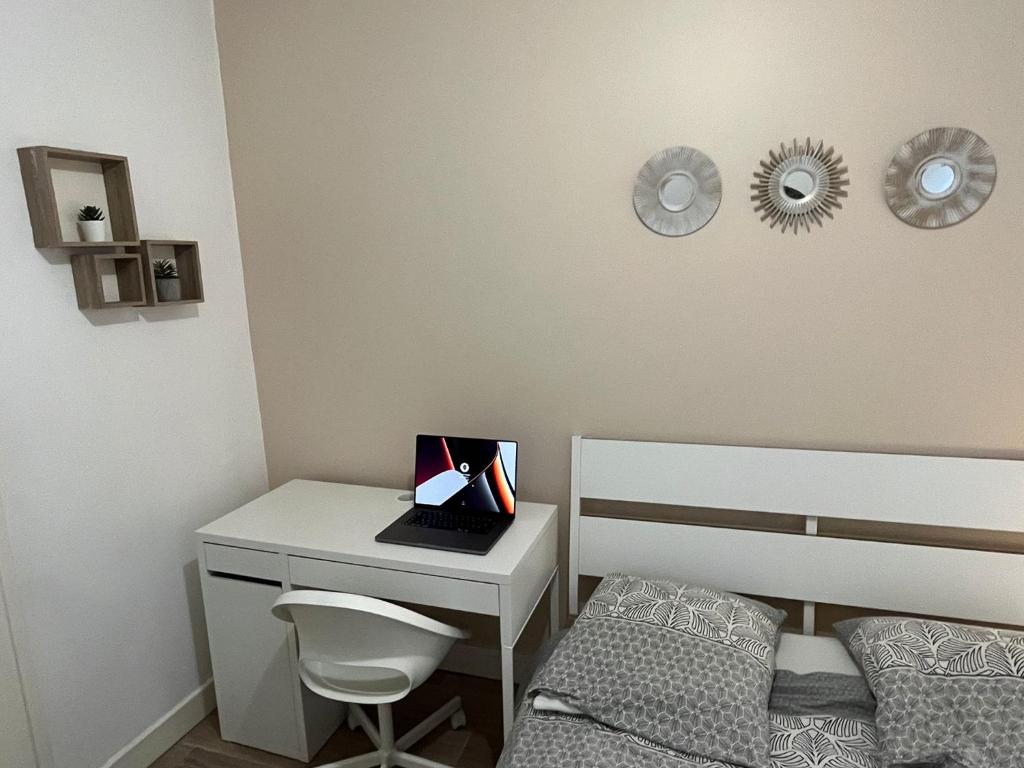 a bedroom with a bed and a desk with a laptop at Appartement Prestige - Amiens in Amiens