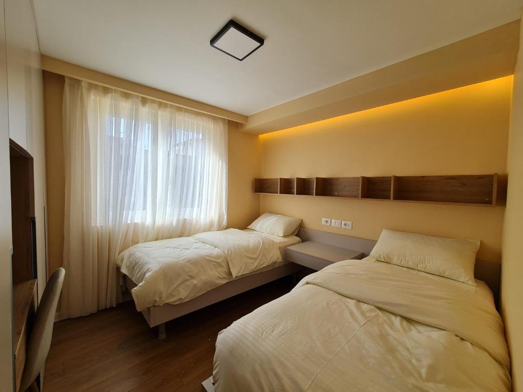 ein Hotelzimmer mit 2 Betten und einem Fenster in der Unterkunft Adore - Modern Apartment in Tirana