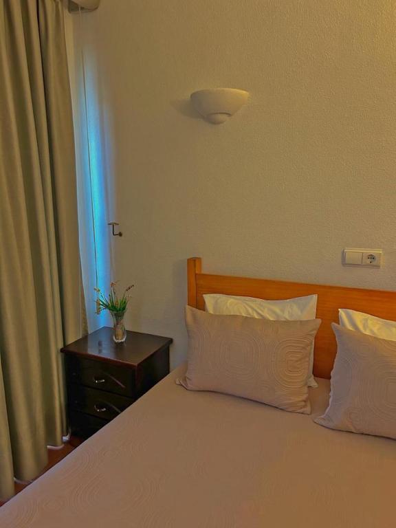a bedroom with a bed with two pillows and a table at Copacabana Residencial in Costa da Caparica