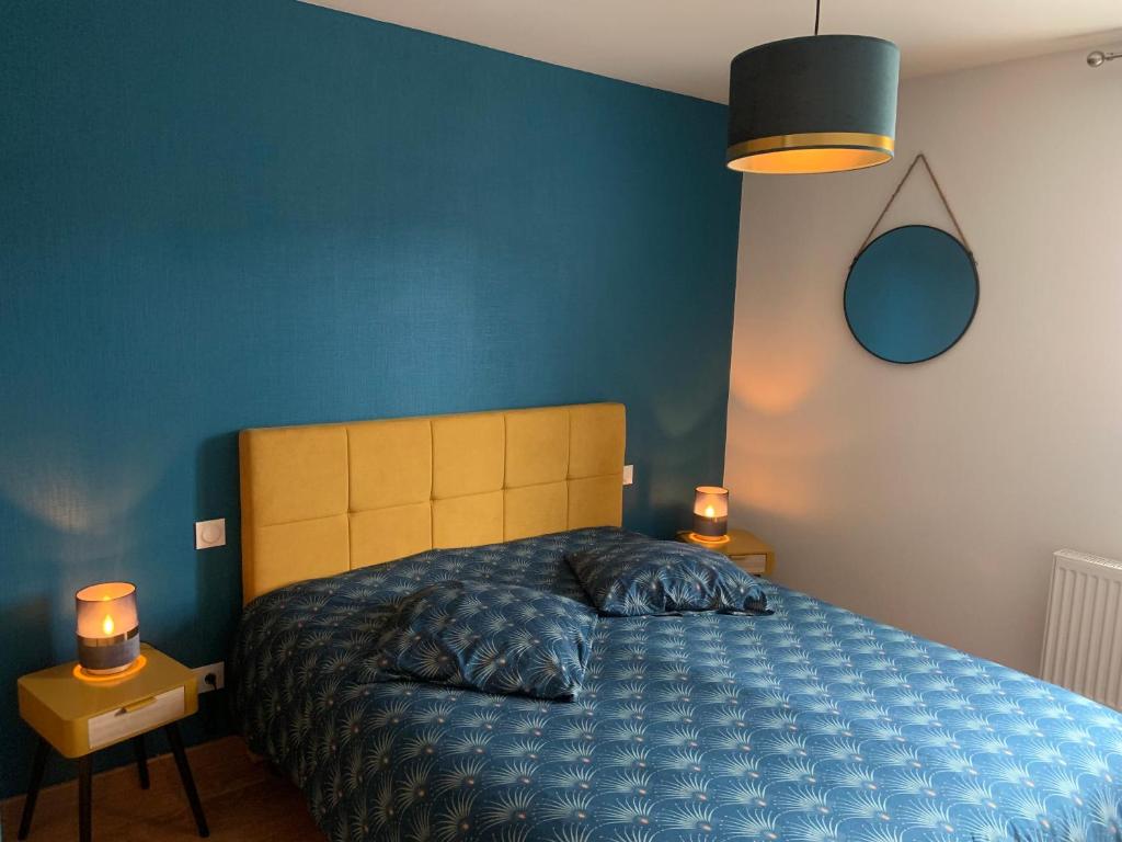 a blue bedroom with a bed and two lamps at Appartement Les Tilleuls &quot;3 étoiles&quot; in Niederbronn-les-Bains