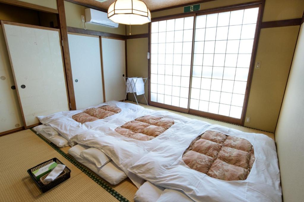 Guest houseTakagi - Vacation STAY 59903v في ماتسوموتو: سرير كبير في غرفة مع نوافذ كبيرة