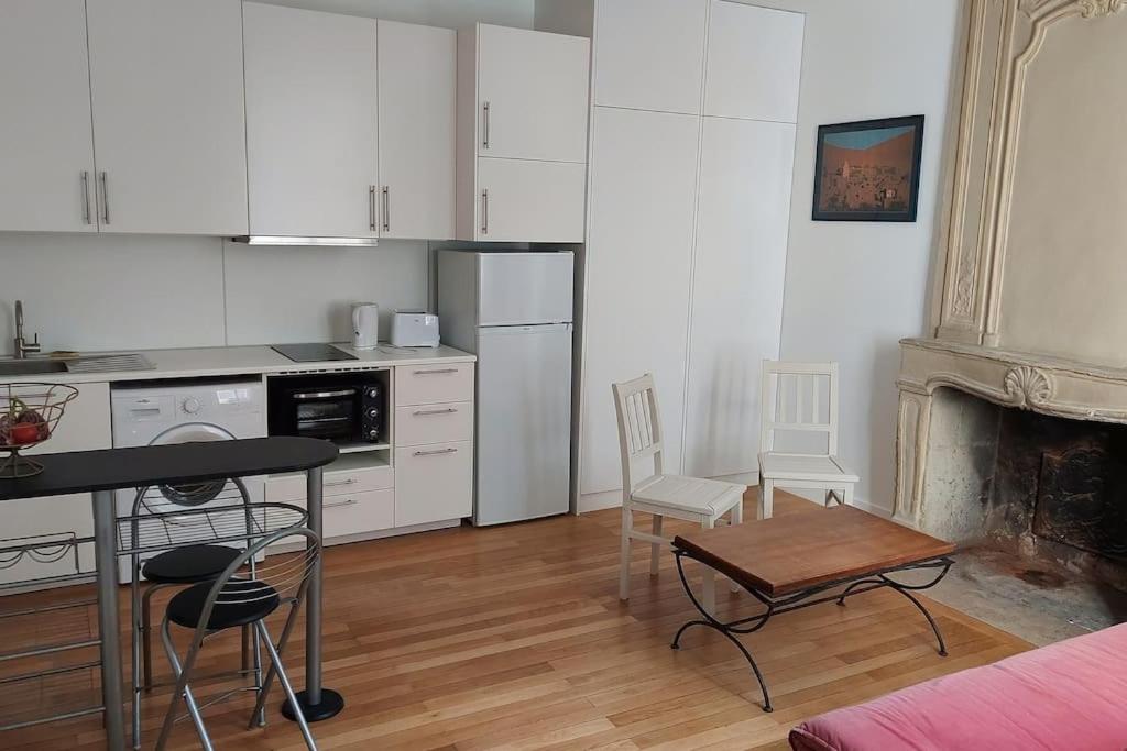 a kitchen with white cabinets and a table and chairs at Appartement 2 pièces proche cathédrale in Nantes